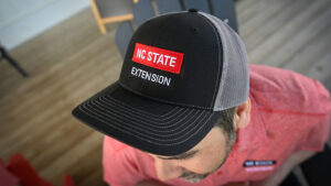 A man wearing an NC State Extension hat.